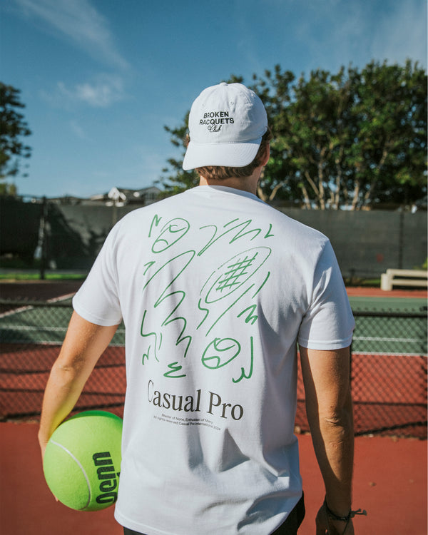 Man wearing a tennis t-shirt with funny graphics and a white dad hat 