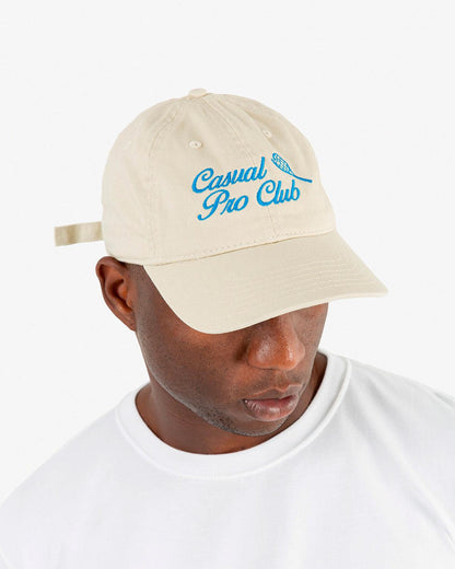 Man wearing a beige tennis hat with embroidered caption, 6 panel hat, low profile