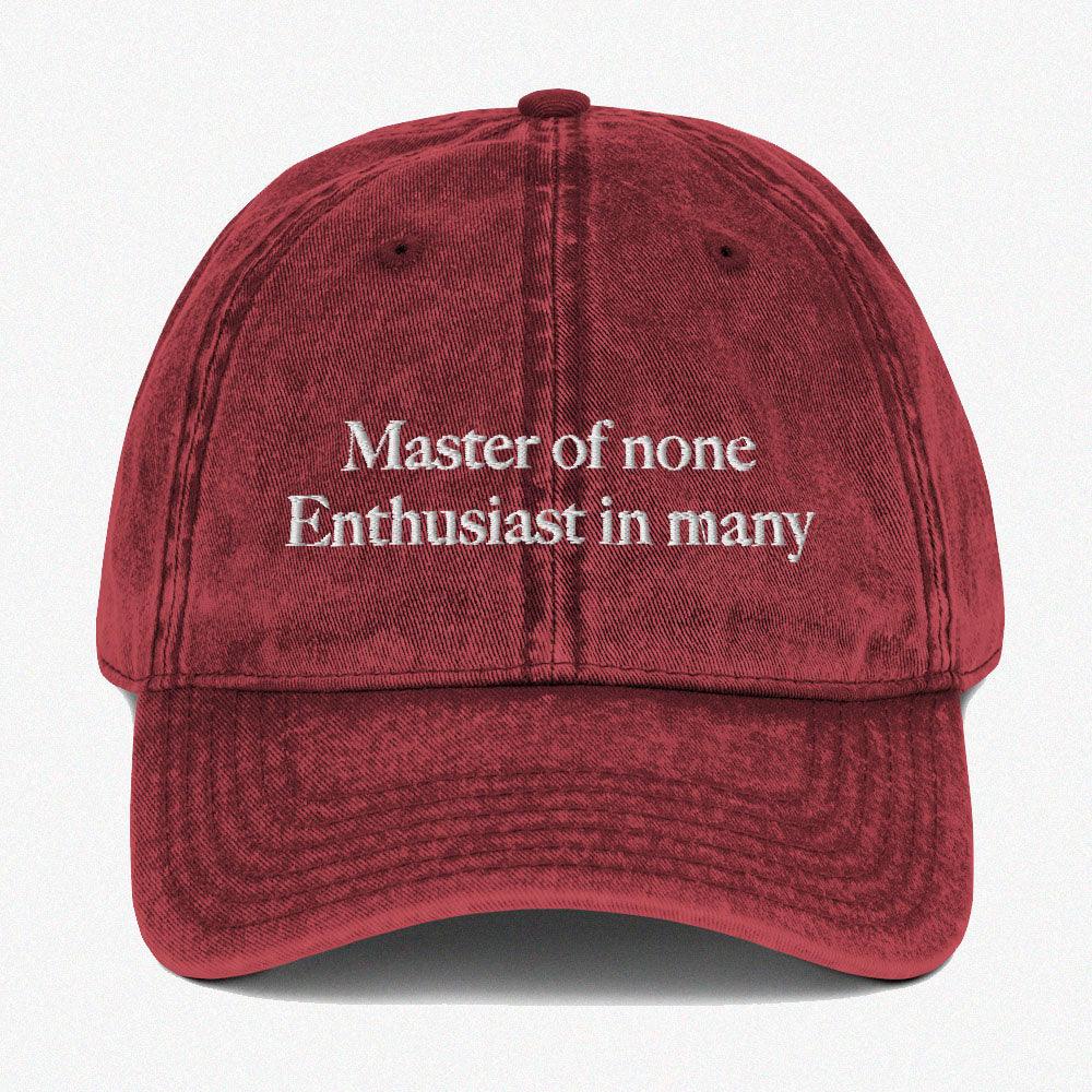 Red Vintage dad hat with embroidered caption at the front: Master of none Enthusiast in many